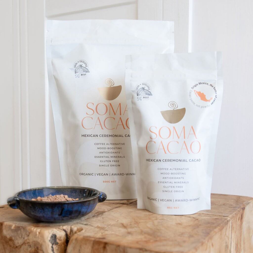 Mexican ceremonial cacao packages with a blue bowl of cacao powder, showcasing premium quality, organic, award-winning product.