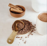 Cacao measuring spoon in gold with cacao powder and cinnamon, perfect for creating premium quality ceremonial cacao drinks.