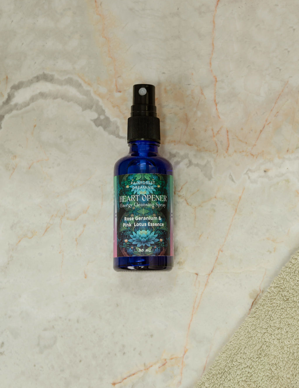 Heart-Opening Cleansing Mist bottle with organic rose geranium and pink lotus essence on a marble surface.