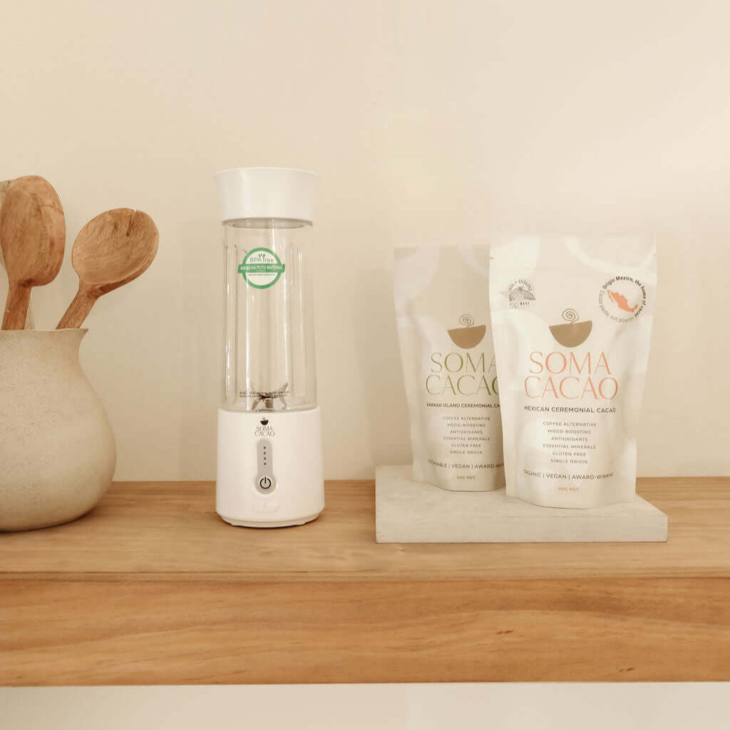 Soma Portable Blender next to Soma Cacao bags on a wooden shelf, showcasing premium quality blending tools for ceremonial cacao.