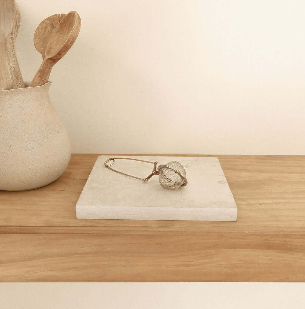 Stainless steel tea strainer on a wooden table, showcasing its ergonomic design and premium quality for brewing ceremonial cacao.