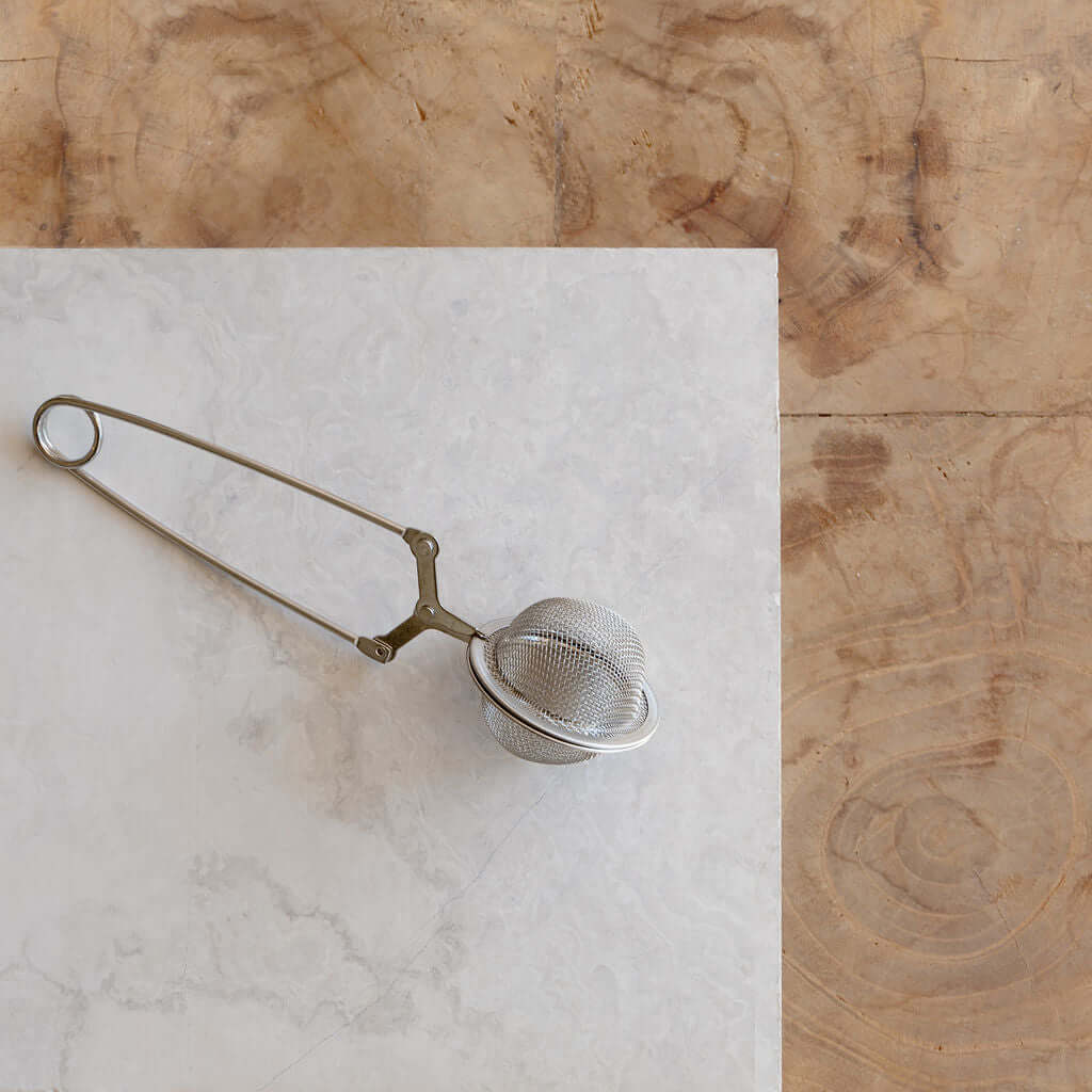 Stainless steel tea strainer on marble surface, fine mesh design for premium quality brewing. Perfect for ceremonial cacao tea.