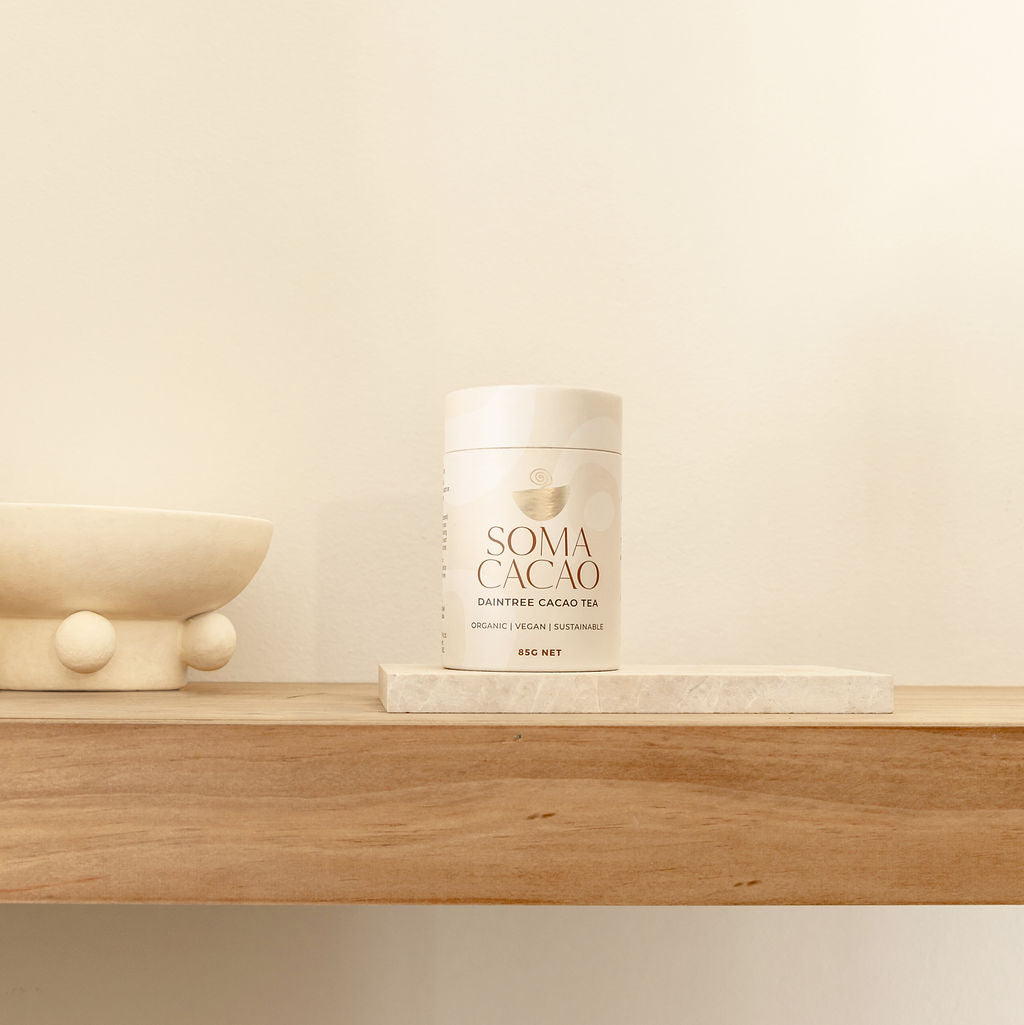 Daintree Cacao Tea by Soma Cacao on wooden shelf with minimalist decor, showcasing premium quality ceremonial cacao.