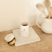Daintree Cacao Tea in a stylish container on a wooden surface with kitchen utensils, showcasing premium quality ceremonial cacao.