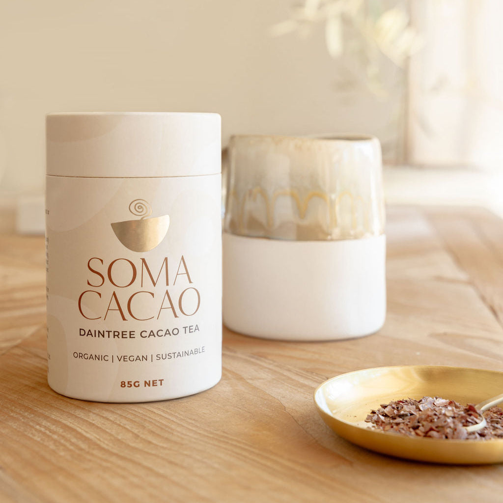 Daintree Cacao Tea by Soma Cacao in an elegant setting with a cup and serving plate on a wooden table.