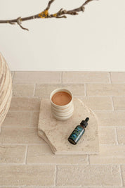 Blue Lotus Flower Essence bottle beside a ceramic cup on a textured stone surface, symbolizing premium quality relaxation.
