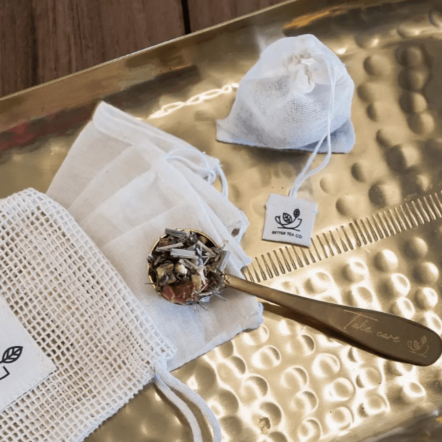 Reusable organic cotton tea bags with loose tea and a spoon on a gold tray by Better Tea Co.